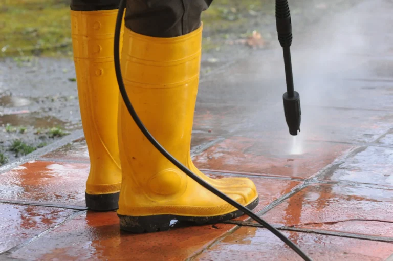 person-wearing-yellow-rubber-boots-with-high-pressure-water-nozzle-cleaning-dirt-tiles copy Image description
